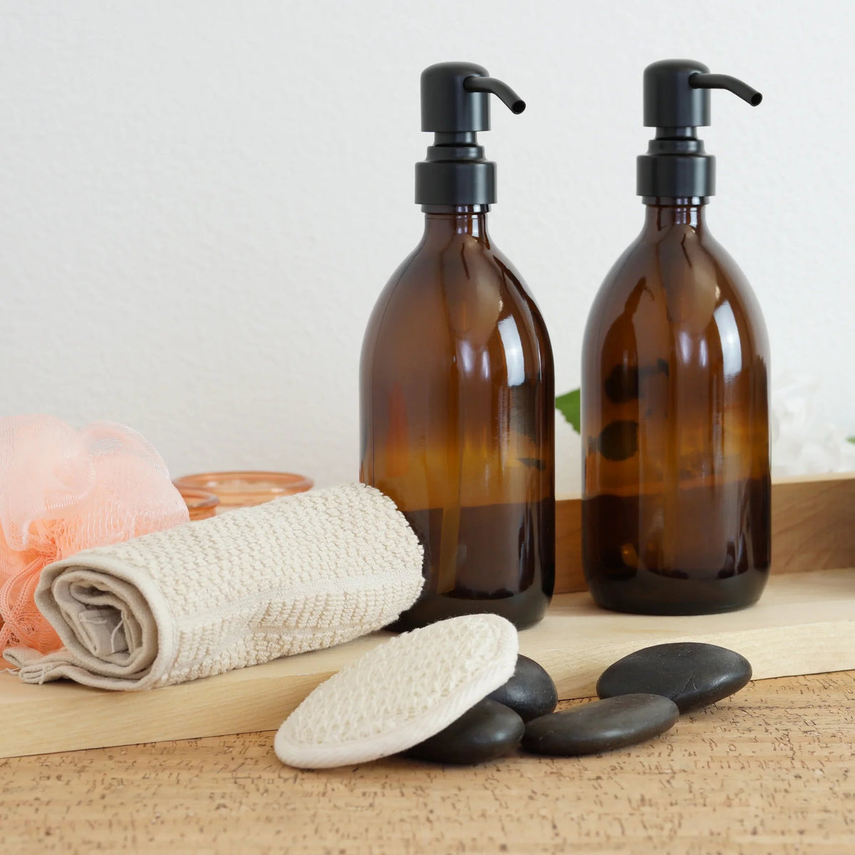 A wooden tray holds two apothecary soap bottles and a soft towel, creating a serene and inviting bathroom display
