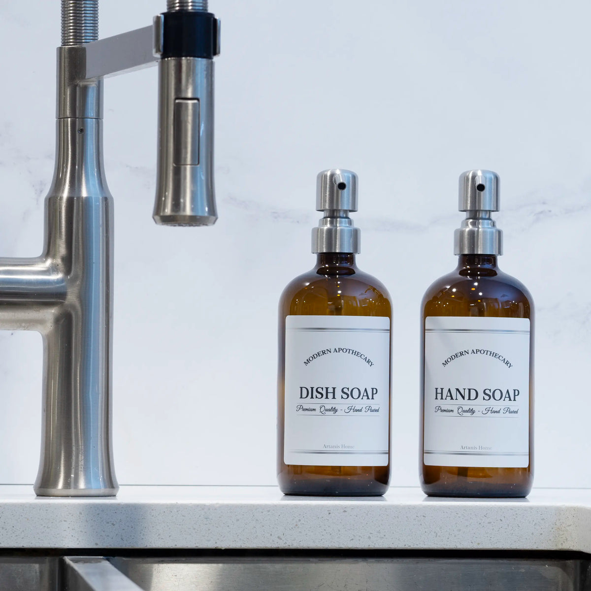 brown glass soap dispensers with hand soap and dish soap labels at a kitchen sink.