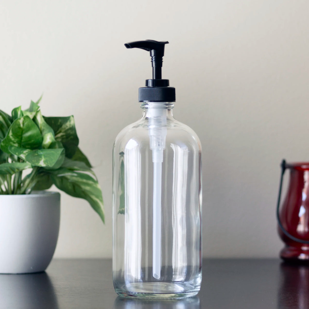 Clear glass 16 oz Boston round bottle with black plastic pump.