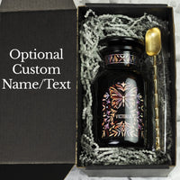 Customized black gift tea jar made of Miron glass in the apothecary style, nestled in a black gift box with an alloy spoon.
