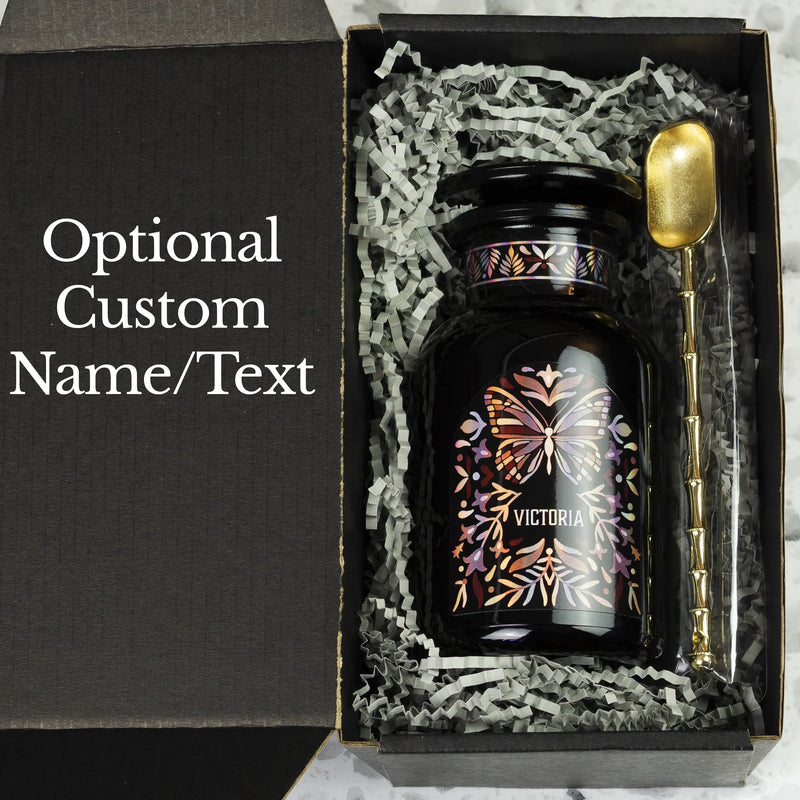 Customized black gift tea jar made of Miron glass in the apothecary style, nestled in a black gift box with an alloy spoon.