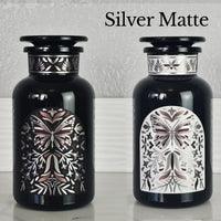 Two Miron violetglass apothecary jars with butterfly labels in white and black.