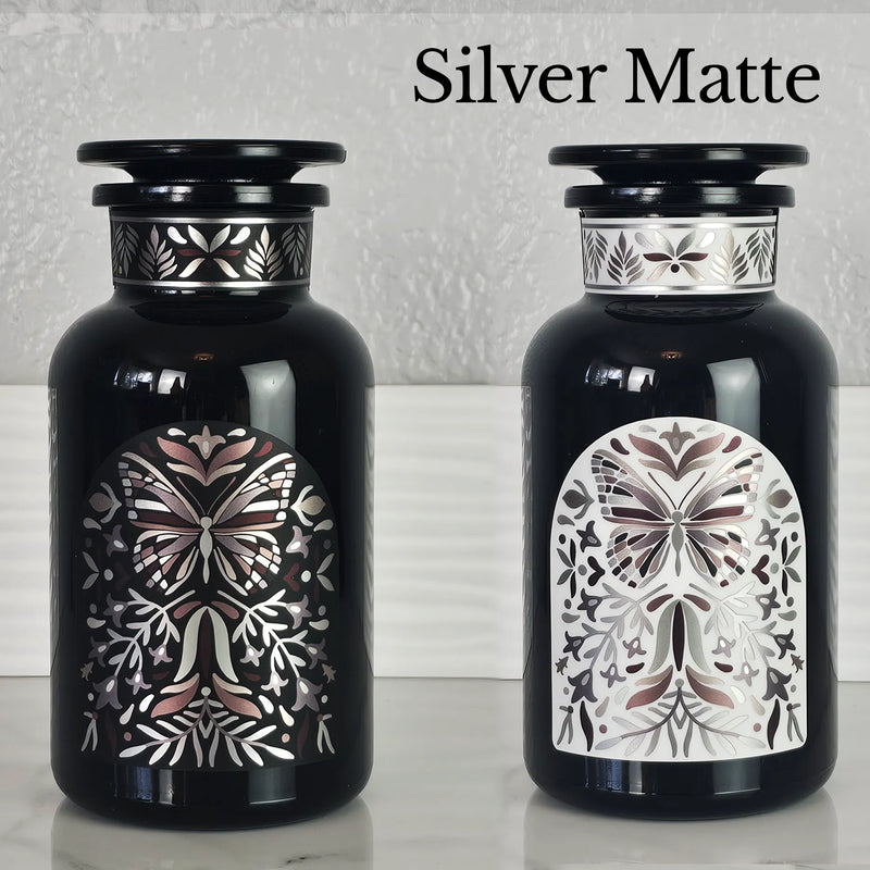 Two Miron violetglass apothecary jars with butterfly labels in white and black.