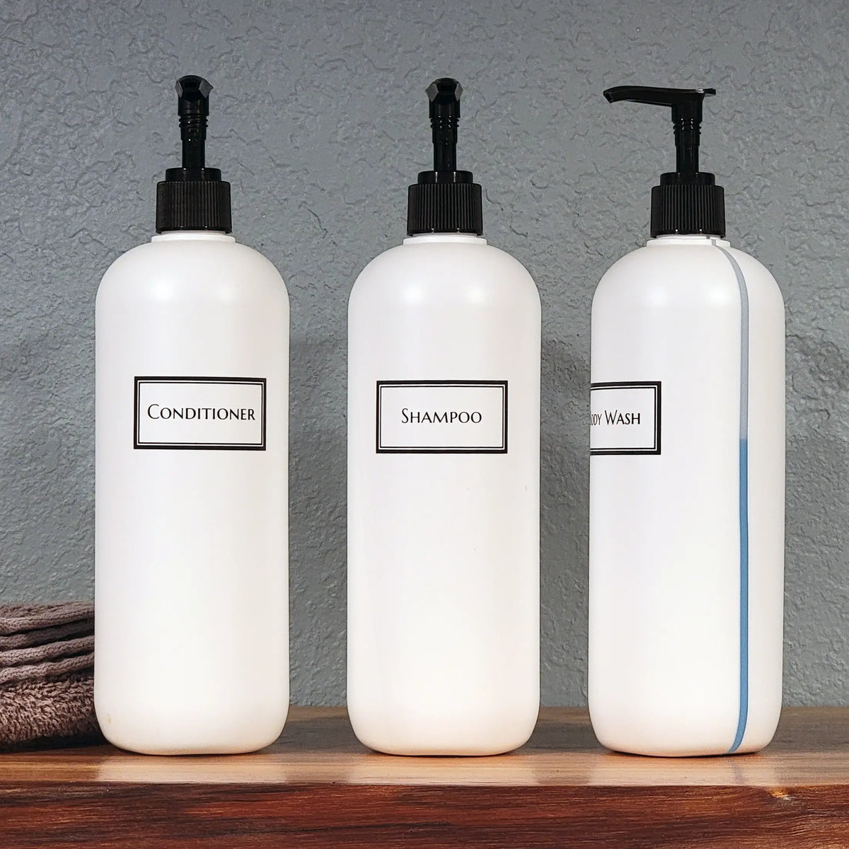 Three white 19oz printed bottles for the shower with one turned to show the view stripe revealing the level of blue body wash.